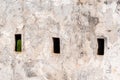 Loopholes and arrowslits on the white wall of a fort