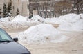 Loose large snowdrift by the road against the backdrop of a city street.