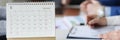 Loose leaf paper calendar standing on table against background of business people closeup Royalty Free Stock Photo