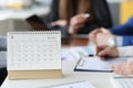 Loose leaf paper calendar standing on table against background of business people closeup Royalty Free Stock Photo