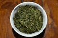 Loose leaves of Chinese green tea in a white porcelain bowl