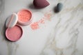 Loose rouge make-up powder with blender sponge on marble beauty table