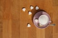 Loose sugar in a pink tea cup and saucer, heart-shaped candies on a wooden table, the concept of excess sugar consumption,