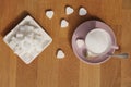 Loose sugar in a pink tea cup and saucer, refined slices, sugar tongs, heart-shaped candies, concept of excessive sugar