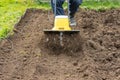 Loosening the soil in the garden beds with an electric hand-held cultivator Royalty Free Stock Photo