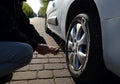 Loosening the wheel at the car to loosen the bolts and replace the wheel tool white black on the street repairman man hands at wor