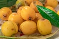 Loquats fruits with green leaves on plate close up