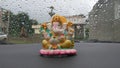 Lord Ganesha idol in car with rain drew background