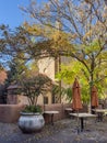Loretto Chapel in the background of courtyard with trees, folded umbrellas, and tables Royalty Free Stock Photo