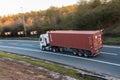 Lorry with brown shipping container in motion on the British motorway M1