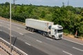 Lorry carrying refrigerated shipping container in motion on British motorway M25
