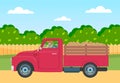 Lorry with potato harvest in the back on a rural field road against a wooden fence and green trees