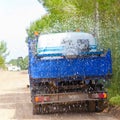 Lorry truck spreading sprinkle water on sand road Royalty Free Stock Photo