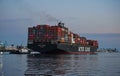 Outbound container ship in the Port of Los Angeles, stacked with cargo containers, steered by a tugboat as it leaves the harbor Royalty Free Stock Photo