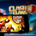 Los Angeles, California, USA - May 25, 2020: Smartphone with the game Clash of Clans on the background of the big screen