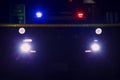 Police car seen in silhouette against search lights and roof light bar Royalty Free Stock Photo