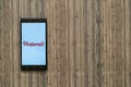 Pinterest logo on smartphone screen on wooden background.