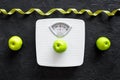 Lose weight concept. Bathroom scale, measuring tape, apples on black background top view Royalty Free Stock Photo