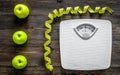 Lose weight concept. Bathroom scale, measuring tape, apples on wooden background top view Royalty Free Stock Photo