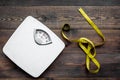 Lose weight concept. Scale and measuring tape on dark wooden background top view