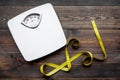 Lose weight concept. Scale and measuring tape on dark wooden background top view Royalty Free Stock Photo