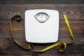 Lose weight concept. Scale and measuring tape on dark wooden background top view Royalty Free Stock Photo