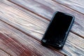 ÃÂ¡loseup black smartphone with broken screen glass lying on wooden table. Concept of dropping phone, broken gadget, electronics