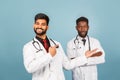 Close-up portrait of a medical worker in a white lab coat with a stethoscope conferring with a young doctor on a blue background