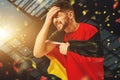 Losing game. Young man, football fan with german flag cheering up football team over dark background with confetti Royalty Free Stock Photo