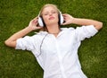 Losing herself to the music. High angle shot of a woman lying on a grassy field listening to music with her eyes closed.