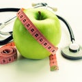 Losing weight - green apple, measuring tape and stethoscope Royalty Free Stock Photo