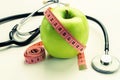 Losing weight - green apple, measuring tape and stethoscope Royalty Free Stock Photo