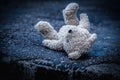 Lost childhood concept. Dirty teddy bear lying down outdoors Royalty Free Stock Photo