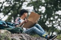 Lost hiker with backpack checks map to find directions near the river in the forest. hiking and adventure concept Royalty Free Stock Photo