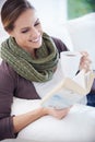 Lost in a page-turner...A young woman relaxing on her couch with a book and a cup of coffee. Royalty Free Stock Photo