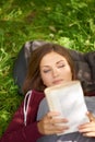 Lost in the story. A lovely young woman reading a book while lying in a field of grass. Royalty Free Stock Photo