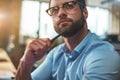 Lost in thougths. Portrait of young bearded man in eyeglasses and formal wear looking away and thinking while working in