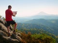 Lost tourist on peak looking into landscape while check paper map, hiking in nature. Royalty Free Stock Photo