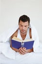 Lost in the world of literature. A man lying comfortably in his bed reading a book.