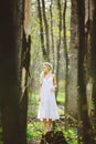 Lost young woman with blond hair in white dress forest among trees. Royalty Free Stock Photo