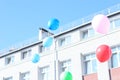 A lot of balloons fly into the blue clear sky, building on the ba Royalty Free Stock Photo