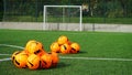 A lot of balls for soccer on a field of artificial grass for training football team. Orange soccer balls on a green artificial Royalty Free Stock Photo