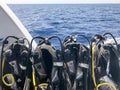 A lot of black diving suit with hoses and divers hanging on a stand on a fast-moving boat, ship, cruise line