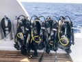 A lot of black diving suit with hoses and divers hanging on a stand on a fast-moving boat, ship, cruise liner in a tropical resort