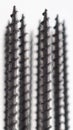 A lot of black long screws stand upright on a white background. Close-up. Hardware, ironware, ironmongery, fasteners, materials