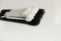 A lot of black mascara brushes are lying on a white background close up on top of them are white shadow applicators Royalty Free Stock Photo