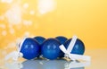 Lot of blue Christmas toys-balls with white ribbon, on yellow background Royalty Free Stock Photo