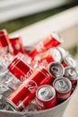 a lot of bottles of coca cola in the steel bowl with ice on wooden table outdoors. fresh beverage ready for summer party