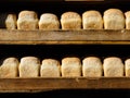 A lot of bread is a brick in a row on a wooden shelf. Fresh bread on the counter of a bakery or pastry shop. Crunchy baked goods. Royalty Free Stock Photo