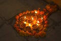 A lot of burning oil candles in a circle of fresh flowers on the street at night time of Diwali